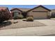 Charming home exterior with desert landscaping, blooming tree and a two-car garage at 9983 W Monterosa Ave, Phoenix, AZ 85037