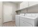 Functional laundry room with white washer and dryer, overhead cabinets, and a convenient access door at 11023 W Chino Dr, Peoria, AZ 85373