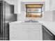 Close-up of the kitchen sink area with white cabinetry and black refrigerator at 11044 N 75Th Dr, Peoria, AZ 85345