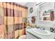 Well-lit bathroom with a single sink vanity and neutral-toned shower curtain at 1179 E Cordova Ave, Casa Grande, AZ 85122