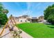 Spacious backyard with green lawn, swing set, and solar panels on the roof, blending sustainability with outdoor enjoyment at 1203 W Escuda Rd, Phoenix, AZ 85027