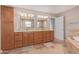 En Suite bathroom features dual sinks, framed mirrors, custom cabinetry, and a separate soaking tub at 3034 E Turney Ave, Phoenix, AZ 85016