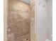 Detailed view of walk-in shower with travertine tile, mosaic accent, and stainless steel fixtures at 3034 E Turney Ave, Phoenix, AZ 85016