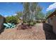 Landscaped backyard featuring a shade tree, rock ground cover, and blue Adirondack chairs with clear blue skies above at 322 N Williams St, Mesa, AZ 85203