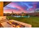 Inviting backyard with a pool, manicured lawn, fire pit, and outdoor seating under a colorful sky at 3408 E Daley Ln, Phoenix, AZ 85050