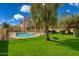 Large backyard with pool and lawn surrounded by a fence and trees under a blue sky at 3641 E Park Ave, Phoenix, AZ 85044