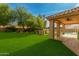 Expansive backyard featuring lush green grass, mature trees, and a covered patio with tiled flooring at 3641 E Park Ave, Phoenix, AZ 85044