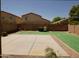 A spacious backyard with concrete patio, faux grass, desert landscaping, and a built-in grill at 43241 W Kristal Ln, Maricopa, AZ 85138