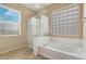 Bright bathroom with a glass shower, large soaking tub, and a window with natural light at 44348 W Windrose Dr, Maricopa, AZ 85138