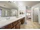 A bathroom with a double sink vanity, large mirror, and a view into the bedroom at 4609 E Ironhorse Rd, Gilbert, AZ 85297