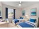Bright bedroom featuring two twin beds, desk, and large window with stylish blue curtains at 4939 E Paradise Dr, Scottsdale, AZ 85254