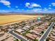 Aerial view of neighborhood featuring pools, lush grass, shade trees, and desert plains at 683 W Honey Locust Ave, Queen Creek, AZ 85140