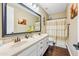 Bathroom with wood-look floors features a double vanity with a large mirror and shower with beige patterned curtains at 683 W Honey Locust Ave, Queen Creek, AZ 85140