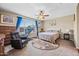 Cozy bedroom with neutral tones features a ceiling fan, comfortable chair, and treadmill by the bright window at 683 W Honey Locust Ave, Queen Creek, AZ 85140