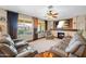 Inviting living room with a fireplace, ceiling fan, plush seating, and large windows offering natural light at 683 W Honey Locust Ave, Queen Creek, AZ 85140
