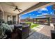 Covered patio with comfortable seating, a ceiling fan, and a view of the landscaped backyard and pergola with a dining set at 683 W Honey Locust Ave, Queen Creek, AZ 85140