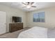 Bright bedroom with a ceiling fan, window with blinds, and tv with dresser at 17296 W Molly Ln, Surprise, AZ 85387