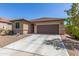 A cozy tan home featuring a brown garage door, desert landscaping, and a spacious driveway at 17296 W Molly Ln, Surprise, AZ 85387