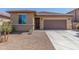 Charming home featuring a brown garage door, desert landscaping, and a cozy front porch at 17296 W Molly Ln, Surprise, AZ 85387