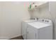 Bright laundry room with modern washer and dryer, storage shelves, and tile flooring at 17296 W Molly Ln, Surprise, AZ 85387