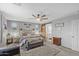 Well-lit main bedroom with a ceiling fan, bench, and decorative wall art at 17935 W Louise Dr, Surprise, AZ 85387
