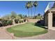 Backyard putting green with desert landscaping and mature palm trees, ideal for outdoor recreation at 2549 E Desert Trumpet Rd, Phoenix, AZ 85048