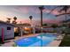 Beautiful backyard oasis with a sparkling pool, covered patio, and lush landscaping at twilight at 2923 N 81St Pl, Scottsdale, AZ 85251