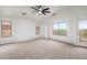 Spacious carpeted bedroom with a ceiling fan, bright windows, and access to a balcony at 3022 N Lainey Ln, Buckeye, AZ 85396