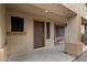 Covered front porch featuring neutral colored walls, a wooden bench and a brown front door at 3022 N Lainey Ln, Buckeye, AZ 85396
