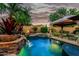 Luxurious backyard with a pool, spa, rock waterfall, and desert landscaping at 3628 E Meadowview Dr, Gilbert, AZ 85298