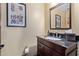 Stylish powder room featuring a dark wood vanity with granite countertop and decorative artwork at 36801 N Long Rifle Rd, Carefree, AZ 85377