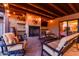 Cozy covered patio with fireplace, wood beam ceiling, sconce lighting and comfortable seating at 36801 N Long Rifle Rd, Carefree, AZ 85377
