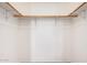 Functional walk-in closet with white walls, a carpeted floor and wooden shelves for easy storage and organization at 3814 W El Camino Dr, Phoenix, AZ 85051