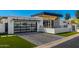 Modern home exterior featuring a glass garage door, gray brick driveway, and manicured lawn at 5822 N 44Th Pl, Phoenix, AZ 85018
