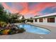 Sparkling pool with rock waterfall feature, lush landscaping, and stunning sunset views at 5822 N 44Th Pl, Phoenix, AZ 85018