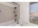 Bright bathroom with a tub and shower combination featuring white tile and black hardware at 7702 W Piute Ave, Glendale, AZ 85308
