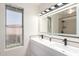 Modern bathroom featuring double sinks, a large mirror, and sleek black hardware at 7702 W Piute Ave, Glendale, AZ 85308