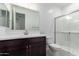 Bathroom with white countertops, dark vanity, tile shower, and glass door at 11408 S 50Th Ln, Laveen, AZ 85339