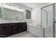 Bright bathroom showcasing a double vanity, soaking tub, and glass-enclosed shower at 11408 S 50Th Ln, Laveen, AZ 85339