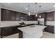 Well-lit kitchen featuring an island with seating, stainless steel appliances, and dark wood cabinetry at 11408 S 50Th Ln, Laveen, AZ 85339