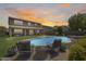Backyard featuring a stunning pool, comfortable lounge chairs, and a well-maintained lawn, set against a colorful sunset at 11875 W Lone Tree Trl, Peoria, AZ 85383