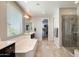 Bright bathroom featuring a soaking tub, a walk-in shower, and a vanity sink at 11875 W Lone Tree Trl, Peoria, AZ 85383