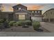 Charming two-story home with desert landscaping, a brick driveway, and a two-car garage, set against a warm sunset backdrop at 11875 W Lone Tree Trl, Peoria, AZ 85383