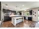 Modern kitchen featuring dark cabinetry, a large island with seating, stainless steel appliances, and hardwood floors at 11875 W Lone Tree Trl, Peoria, AZ 85383