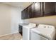 Well-equipped laundry room featuring dark wood cabinets, counter space, and modern washer and dryer at 11875 W Lone Tree Trl, Peoria, AZ 85383