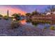 Community entrance includes a pond with a waterfall and desert landscaping, lit by a colorful sunset at 11875 W Lone Tree Trl, Peoria, AZ 85383