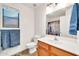 Bright bathroom featuring a wood vanity, shower with decorative curtains and bath towels by the window at 15019 W Banff Ln, Surprise, AZ 85379