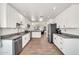 Open kitchen features white cabinets, stainless steel appliances, granite counters, and wood-look tile floors at 15019 W Banff Ln, Surprise, AZ 85379