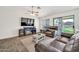 Cozy living room with wood-look tile, ceiling fan, and sliding glass doors to the backyard at 15019 W Banff Ln, Surprise, AZ 85379