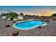 Beautiful backyard pool area features decorative rock landscaping and a calming sunset at 15019 W Banff Ln, Surprise, AZ 85379